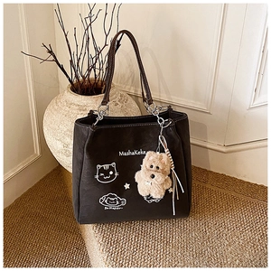 Dettaglio borsa shopper nera con stampe graffiti e un simpatico ciondolo orsetto di peluche