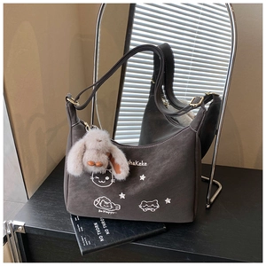 Detalle del bolso bandolera gris con bordado de gato y colgante de conejo de peluche suave