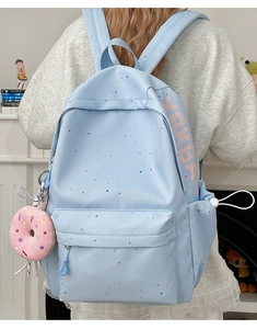 Detail of light blue polka dot backpack with a cute pink donut plush keychain accessory