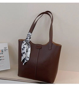 Detail of dark brown lychee leather tote bag with a decorative floral silk scarf on handle