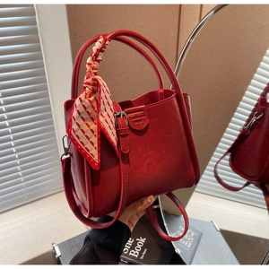 Detail of red faux leather bucket bag with silk scarf handle and adjustable strap