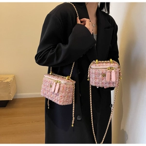 Detail of pink tweed mini bag with golden camellia ornament and chain strap worn by model
