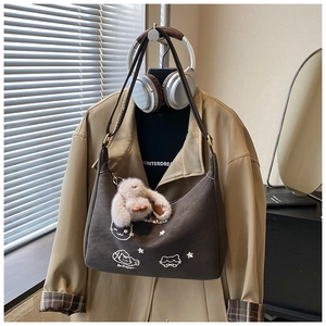 Detalle del bolso de hombro creciente café con bordado de gato y colgante de peluche
