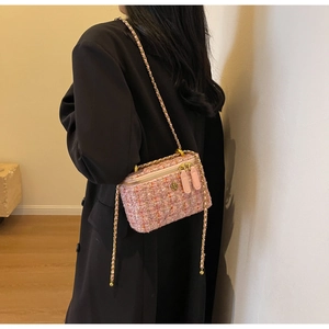 Pink tweed crossbody bag with gold chain strap shown on model from back view