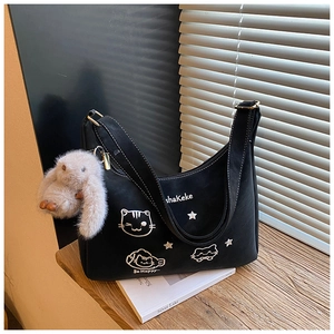 Detalle de bolso de lona negra con bordado de gato y un colgante de conejo de peluche