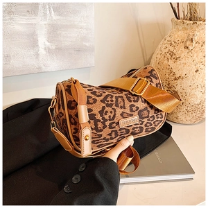 Detail of leopard print cylinder bag with a wide strap on a stylish blazer background