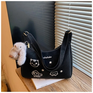 Detalle de bolso hobo negro con bordado de gato blanco y un dije de conejo de peluche