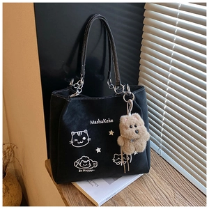 Dettaglio borsa tote in pelle scamosciata nera con ricamo di gatto e ciondolo a orsetto