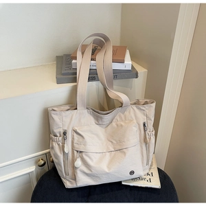 Détail du grand sac cabas en nylon beige avec poche zippée et rangements latéraux