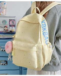 Detail view of yellow polka dot backpack with plush donut charm and blue brand lettering