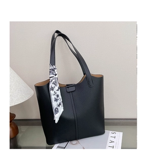 Detail of black lychee grain leather tote bag with floral scarf on handle and beige lining