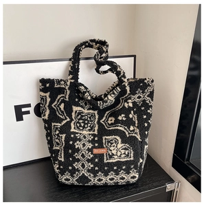Macro detail of plush black and white bandana pattern tote bag with leather logo patch