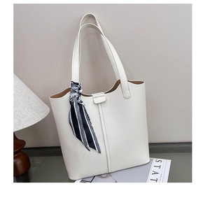 Detail of off-white lychee leather tote bag featuring a striped silk scarf and magnetic clasp