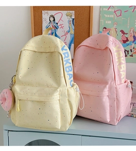 Detail of pink and yellow canvas backpacks with colorful polka dots and cute donut charms