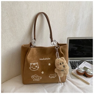 Dettaglio della borsa tote in pelle scamosciata marrone con ricamo gatto e ciondolo orso