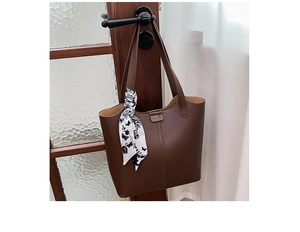 Close-up of a dark brown lychee leather tote bag featuring a decorative floral silk scarf