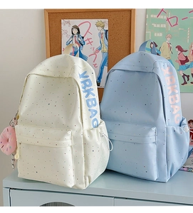 Detail of canvas student backpack showing colorful dots and cute doughnut pendant decoration