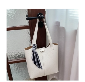 Detail of white lychee grain tote bag with striped silk scarf on a wooden door