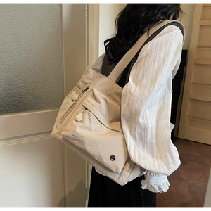 Detailansicht der beigen Tragetasche mit Multi-Pocket-Design und Reißverschluss-Details