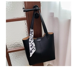 Detail of black pebbled leather tote bag with elegant floral scarf on the handle