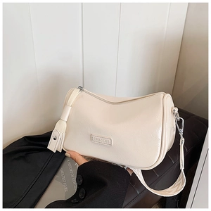 Close-up of cream pillow bag with pleated texture and stylish geometric wide strap