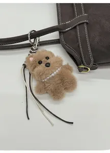 Brown plush bear keychain with pearl necklace and bone tag on a leather shoulder bag