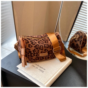 Macro detail of leopard print cylinder bag with branded patch and orange nylon strap