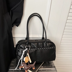 Detalle de bolso tipo almohada de cuero PU negro con colgante de teckel en maleta plata