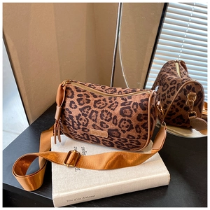 Detailed close-up of leopard print pillow bag with woven strap and tassel charm