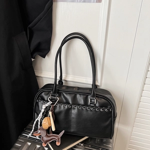 Detalle de bolso de hombro en ecocuero negro con cuerda trenzada y colgante de cachorro