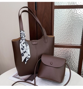Detail of dark brown pebble leather tote bag with printed silk scarf on a table