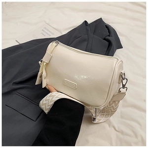 Close-up of cream pillow bag featuring pleated leather texture and geometric jacquard strap