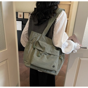 Vue détaillée du sac cabas en nylon vert clair avec design multi-poches et bandoulière
