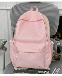 Pink student backpack with colorful dots and VRKD branding on a cozy study chair