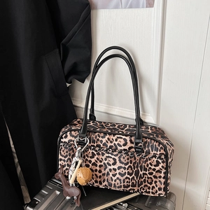Detalle de bolso de hombro con estampado de leopardo, asas negras y colgante de perro