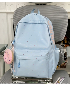 Detail of light blue school backpack with colorful dots and pink doughnut plush charm
