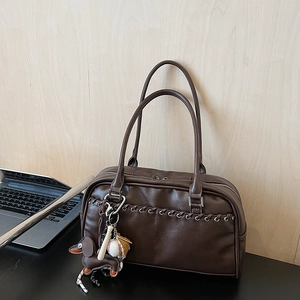Detalle de un bolso retro de cuero marrón con correas tejidas y dijes decorativos