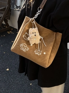 Borsa tote marrone opaca con illustrazione di gatto e ciondolo di peluche su modella