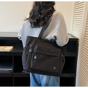 Détail du sac cabas en nylon noir avec poche zippée et compartiment latéral plat
