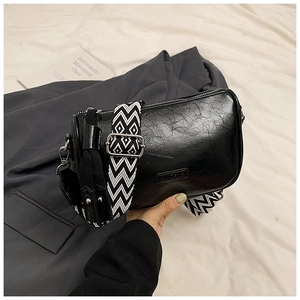 Detail of vintage black pillow bag with textured faux leather and wave pattern strap