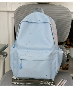 Detail of light blue student backpack with colorful confetti patterns on stacked books