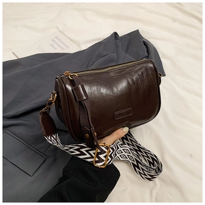 Detail of dark brown leather pillow bag with stylish black and white woven strap