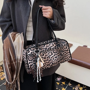 Detalle de bolso de hombro con estampado de leopardo, asas de cuero y colgante de poni