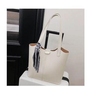 Close-up of white pebble leather tote bag with stylish patterned scarf on handle