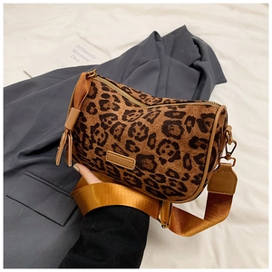 Close-up of leopard print cylindrical bag with wide mustard strap and bronze hardware