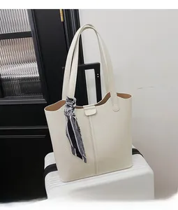 Close-up of a cream-white lychee leather tote bag featuring a decorative silk scarf on the strap