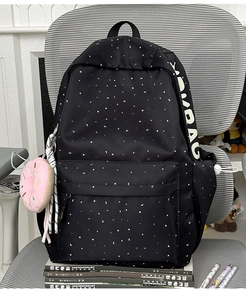 Detail of black canvas backpack with star patterns and pink donut plush charm accessory