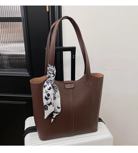 Detail of dark brown lychee leather tote bag with a floral scarf on the shoulder strap