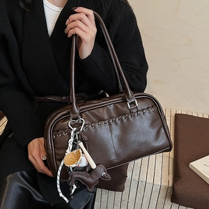 Detalle del bolso tote marrón oscuro con costuras en contraste y colgantes
