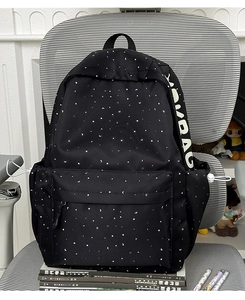 Detail of black student backpack with moon-star pattern and YOMBAG logo on side pocket